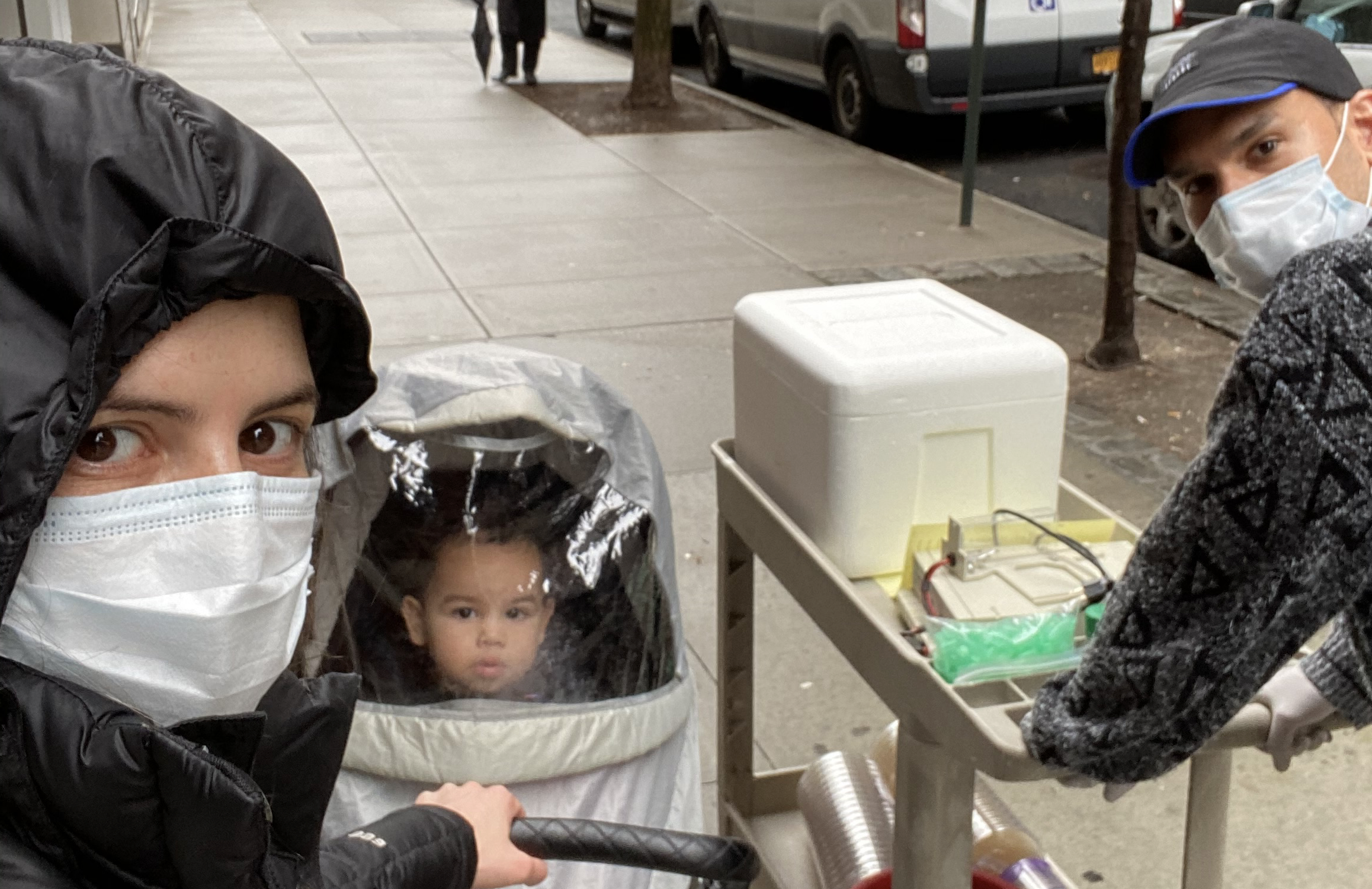 Dr. Sánchez-Rivera and Dr. Soto-Feliciano steering a cart of supplies along with their toddler in a stroller down East 68th Street.