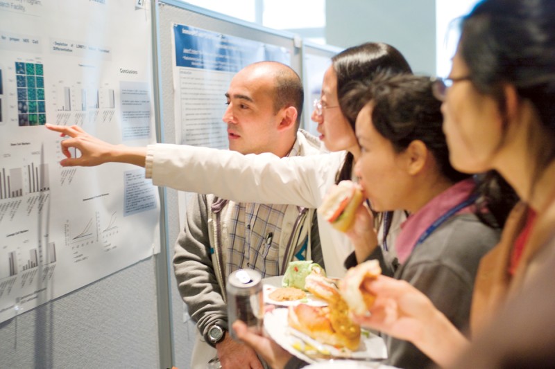 Postdoctoral researchers discuss a poster presentation