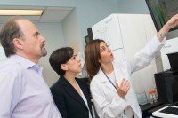 Three scientists look up at ascreen showing genetic information about a tumor.