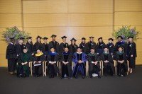 Graduates and speakers pose on a stage