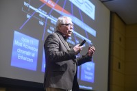 Male scientist speaking in front of a screen