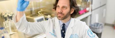 MSK physician-scientist Christopher Klebanoff in lab looking at slide.
