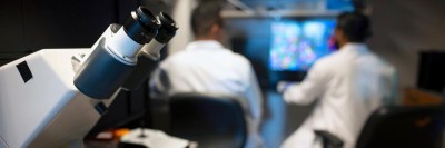 Microscope in foreground, MSK researchers in the background.